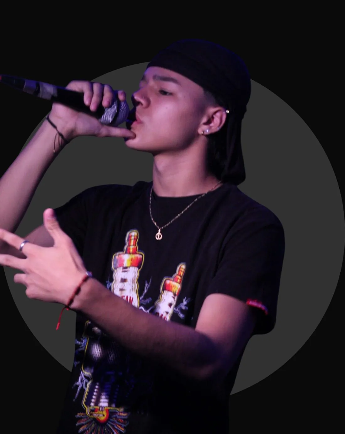 Mainyy interpretando con micrófono, fondo de círculo